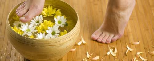 woman dipping foot into water with flowers